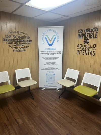 Sala de espera de la Clínica de la Voz Concepción, con sillas, un pendón de VozClinic y frases en las paredes.